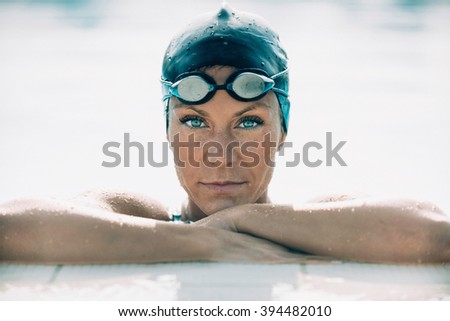 Portrait of a female swimming champion, hanging by the side of a pool