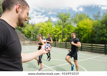 Sports trainer with stopwatch, cardio training outdoors