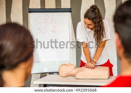 CPR class with instructors talking and demonstrating firt aid, compressions ans reanimation procedure. Cpr dummy on the table.
