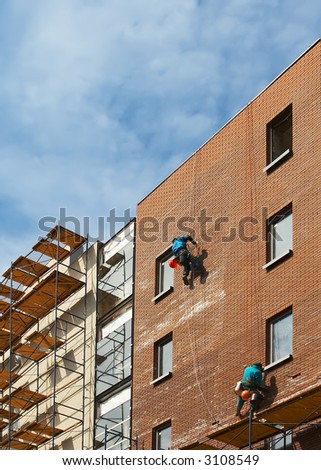Builders on a wall of a builded brick building