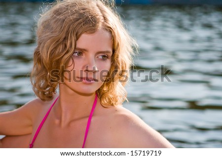 Beautiful girl in beams of the coming sun on a background of water with waves