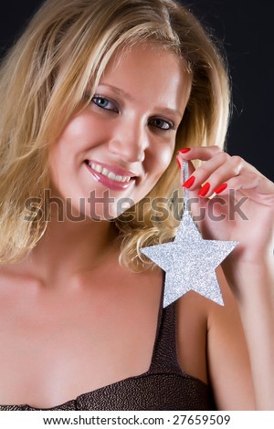 Beautiful girl with a silver star in a hand against a dark background