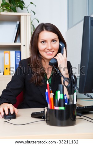 Business woman speaks by phone and works on the computer