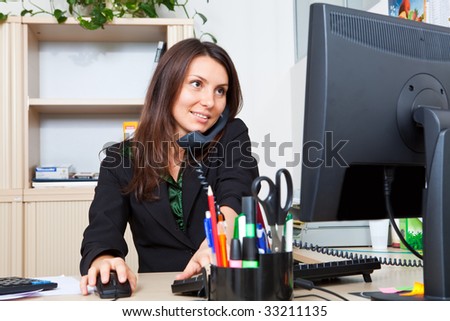 Business woman speaks by phone and works on the computer