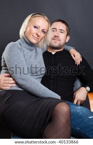 Man and woman sit against a dark background