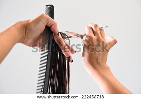 Close up of beautician\'s hand with a comb cutting hair of woman