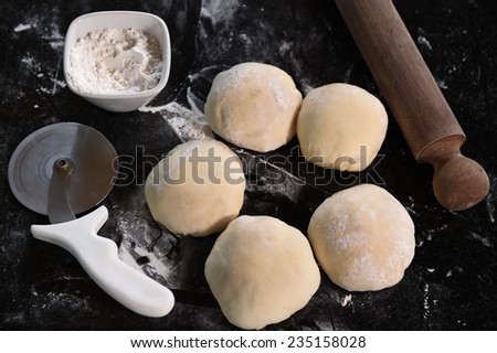 Small balls of fresh pizza dough on wooden board.