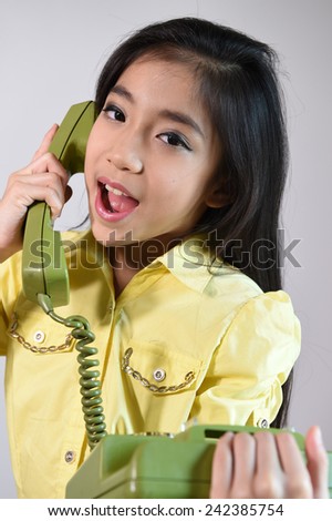 The beautiful little girl in vintage style talking on phone.