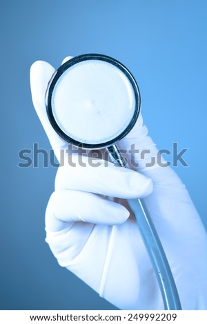 Hand holding a stethoscope take with blue filter