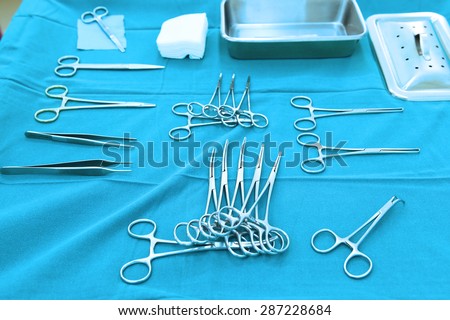 Detail shot of steralized surgery instruments with a hand grabbing a tool take with blue filter