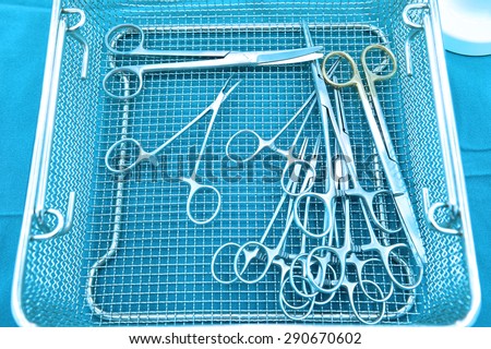Detail shot of steralized surgery instruments with a hand grabbing a tool take with art lighting and blue filter