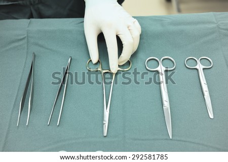 Detail shot of steralized surgery instruments with a hand grabbing a tool take with selective color technique and art lighting
