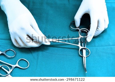 Detail shot of steralized surgery instruments with a hand grabbing a tool take with art lighting and blue filter