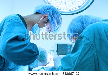 two veterinarian surgeons in operating room take with art lighting and blue filter