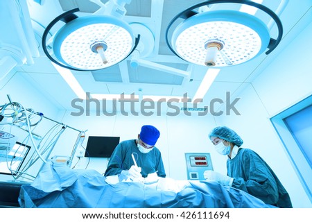 two veterinarian surgeons in operating room take with art lighting and blue filter