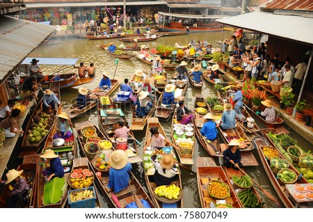 BANGKOK â  APRIL 13: Wooden boats busy ferrying people at Amphawa floating market on April 13, 2011 in Bangkok. A traditional popular method of buying and selling still practiced in Amphawa canals of Thailand.