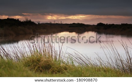 Dusk over a water channel at RSPB Mersehead Nature Reserve, Southwick, Dumfries and Galloway, Scotland, UK.