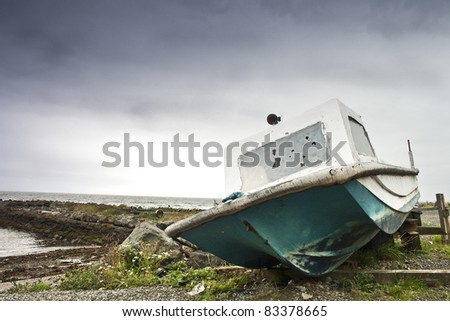 An old abandoned, broken fishing boat on the shore in Dunure in Scotland.