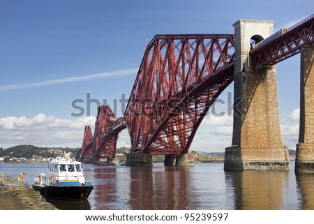 Train on Forth Rail Bridge with boat being washed in foreground. The rail bridge crosses the firth of forth from Lothian to Fife, Scotland. Taken from South Queensferry.