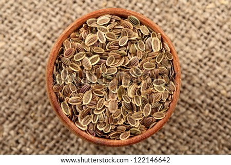 spices - fennel, dill seeds (Anethum graveolens) in a wooden bowl on sacking. The plant is used in medicine, in perfumery and cosmetics,