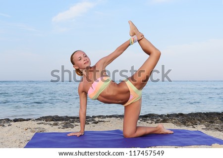 Yoga practice. Slim woman practicing yoga asana by the sea