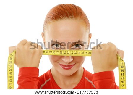 Beautiful slim red fit woman holding measuring tape to her face over white background
