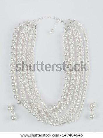 Pearls necklace with earrings on grey paper background