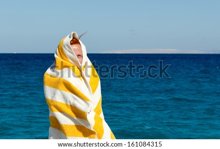 Young woman covers herself with beach towel because of winter wind in Egypt