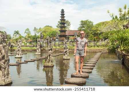 Happy tourist at Tirtagangga water palace with fountains  and ponds on Bali, Indonesia