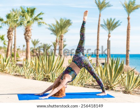 Woman doing down dog yoga asana at the beach