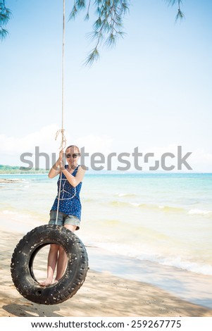 Happy woman having fun on tire swing at the beach. Phu Quoc, Vietnam