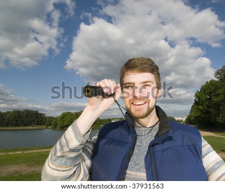 Young man holding spyglass expresses positivity on a sunny day in the park.