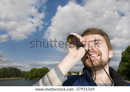 Young man hangs out in a park playing with his spyglass.