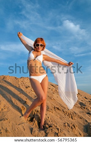 Beautiful red girl wearing bikini with scarf on the sand