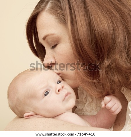 Loving young mother kisses her newborn son