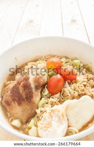 Instant noodle\
Grilled Chicken\
boiled egg\
onion\
Pork soup\
In a white cup\
Placed on the wooden floor