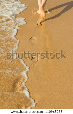 Vacation on sea shore, footprints on sand, feet running through surf