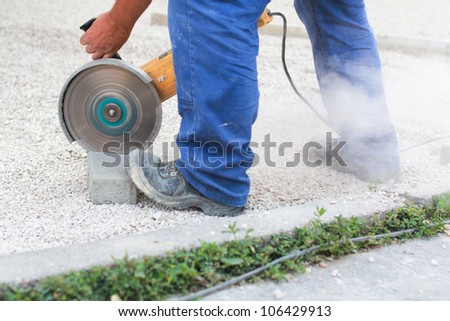 Worker cutting grey brick with circular buzz saw