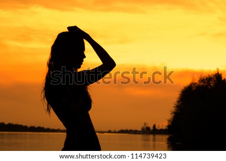 Beautiful dancing woman hands up sunset silhouette
