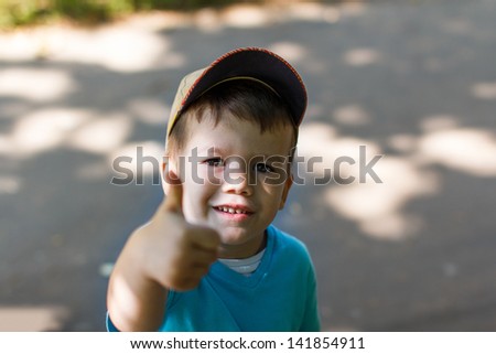 Little boy in cap with victory sign, outdoors