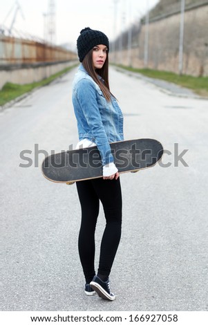 Woman holding skateboard, looking back