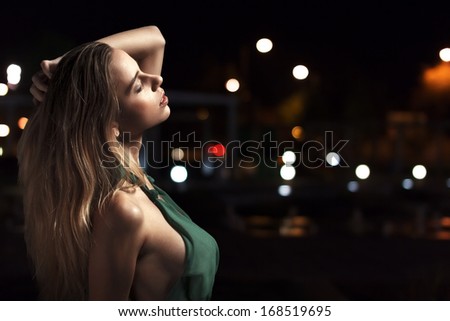 Sensual woman posing at night, city lights background