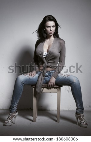 Sexy brunette woman with big tits sitting on stool