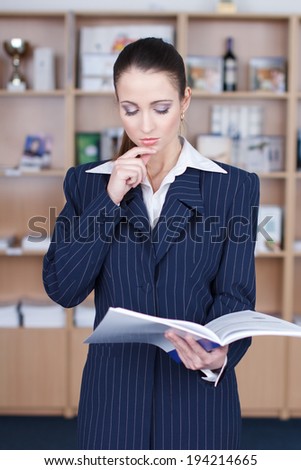 Businesswoman reading product catalog and thinking in office
