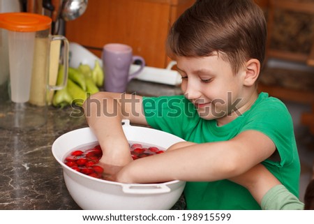 Six year old caucasian boy eating cherry from bowl