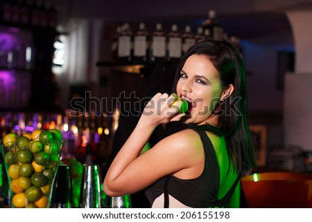 Young brunette woman in bar bite fruit