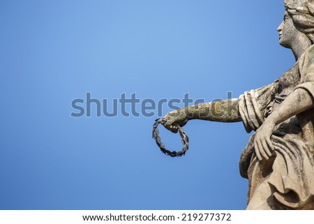 Stone sculpture of virgin holding wreath, architectural background, Komarno, Slovakia