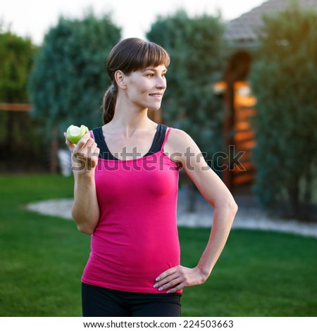 Brunette woman eating fresh apple, outdoor portrait, healthy lifestyle