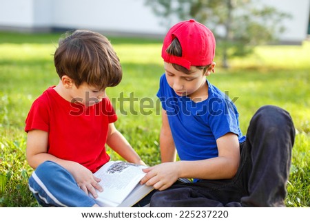 Little brothers reading book in nature, education