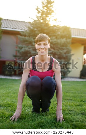 Fresh sporty woman squat outdoor teeth smile